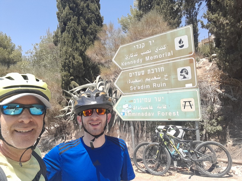 Cyclists at the Kennedy Memorial and Amminadav Forest trail signs